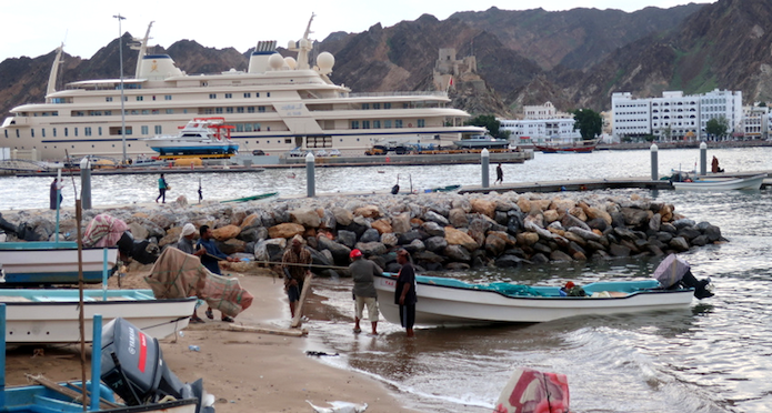 Рыбацкая лодка и бежевая яхта султана Кабуза на заднем фоне